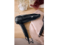 Secador de cabelo preto e escova numa mesa de madeira com uma toalha rosa.