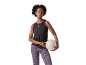 Mulher com top preto e leggings de leopardo roxas, segurando uma bola de fitness.