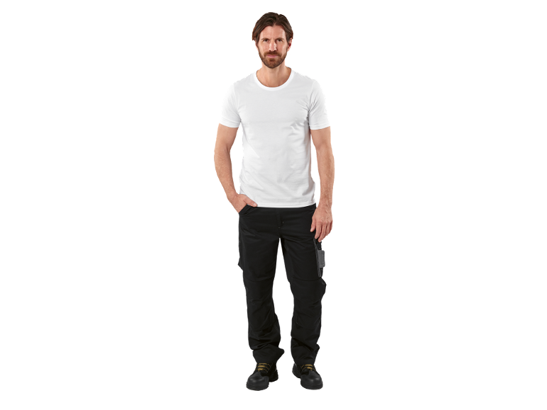 Homem de t-shirt branca e calças de trabalho pretas com botas de segurança.