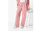 Mulher com calças de fato rosa e casaco a condizer, com sapatilhas brancas.