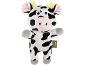 Vaca de pelúcia preta e branca com chifres amarelos e nariz rosa.