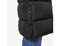 Detalhe de um casaco acolchoado preto com botões de pressão sobre jeans azuis.