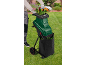 Um triturador de jardim verde com rodas, com folhas a serem trituradas para um saco preto.