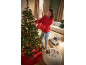 Mulher decora árvore de Natal com luzes e enfeites, presentes e decorações no pufe.