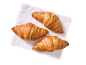 Três croissants dourados sobre um guardanapo branco, vistos de cima.