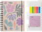 Um caderno em espiral com padrão floral e elástico, ao lado de uma régua com notas adesivas.