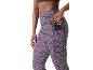 Mulher com leggings de padrão leopardo lilás com um bolso lateral para o telemóvel.