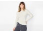 Mulher com camisola de manga comprida creme e jeans escuros.
