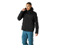 Homem com casaco softshell preto com capuz e calças azuis de exterior