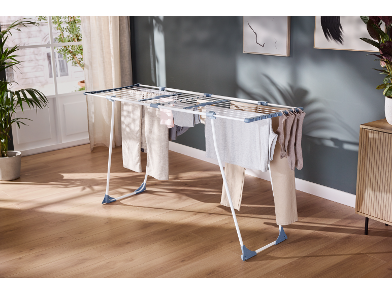 Estendal de roupa com peças de vestuário a secar numa sala iluminada