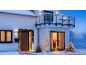 Casa com luzes de Natal, árvores de Natal e uma rena iluminada na neve.