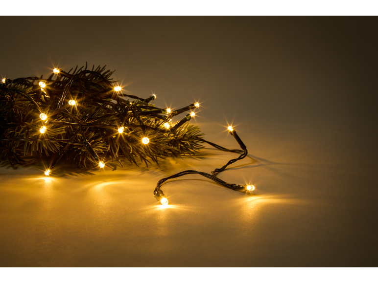 Luzes de Natal quentes em ramos de pinheiro, criando um ambiente festivo.