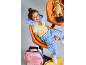 Menina feliz com almofada de viagem, mala e leão de peluche numa área de espera.