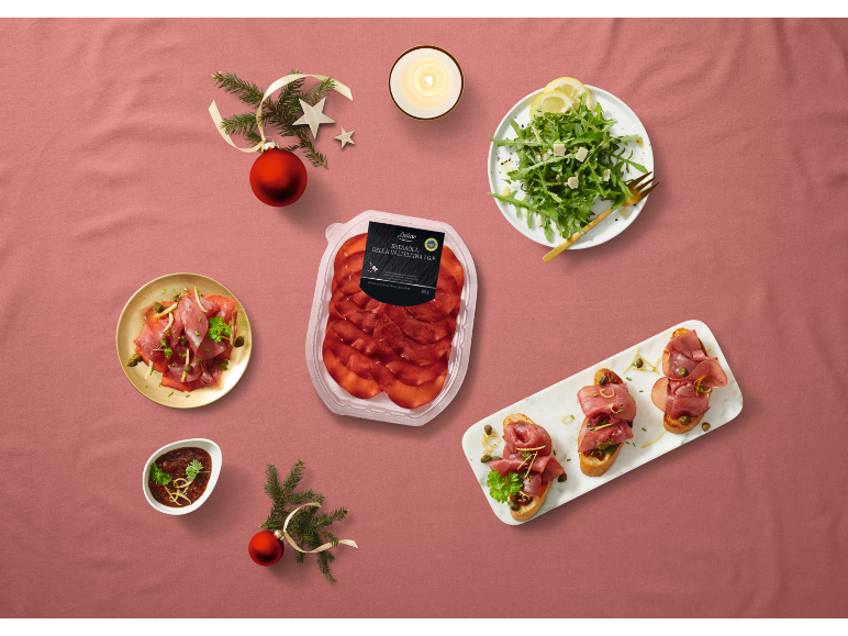 Pratos de presunto, salada e bruschetta, com decorações de Natal.