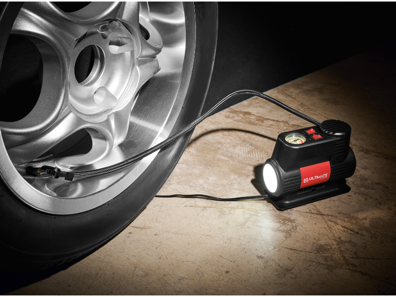 Inflador de pneus portátil com luz embutida conectado a um pneu de carro.