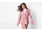 Mulher com um fato de blazer rosa de trespassar e calças a condizer.