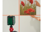 Nível laser verde projetando linhas vermelhas numa parede enquanto alguém pendura um quadro.