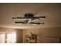 Candeeiro de teto preto moderno com fitas LED integradas e efeito de céu estrelado numa sala.