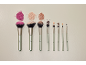 Conjunto de nove pincéis de maquilhagem com pós soltos e bases líquidas.
