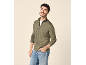Homem sorridente com casaco verde com fecho e jeans.