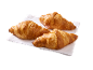 Três croissants dourados sobre um guardanapo branco, prontos para saborear.
