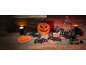 Decorações de Halloween com abóboras, morcegos, velas e uma garrafa numa mesa de madeira.