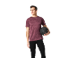 Homem com t-shirt desportiva bordeaux e leggings pretas, a segurar uma bola medicinal.