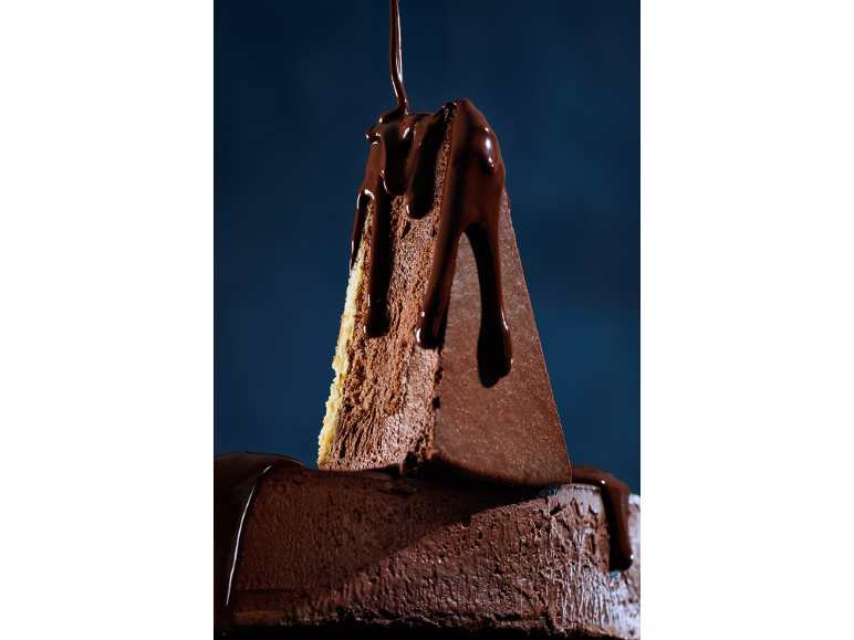 Bolo de chocolate com calda de chocolate escuro, com uma fatia cortada.