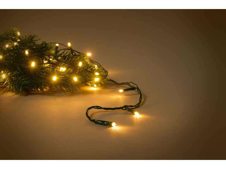 Ramos de abeto com luzes de Natal quentes sobre um fundo castanho.