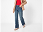 Mulher com blazer bege, top vermelho, jeans largos e sapatilhas cor-de-rosa.