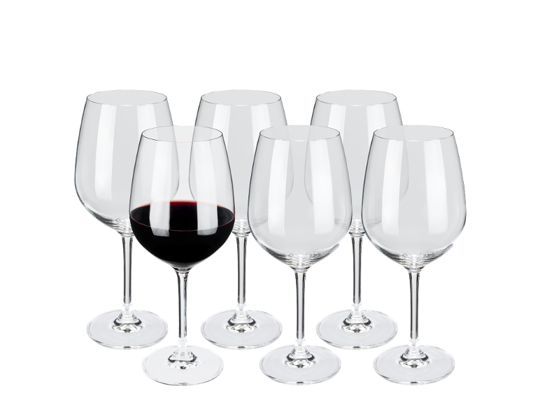 Seis copos de vinho, um cheio de vinho tinto, sobre fundo preto.
