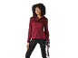 Mulher com casaco com capuz cor de vinho e leggings pretas segurando bastões de trekking.