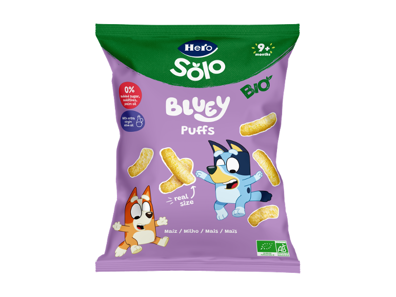 Embalagem roxa de puffs de milho para crianças com personagens de desenhos animados e o texto '9+ meses'.