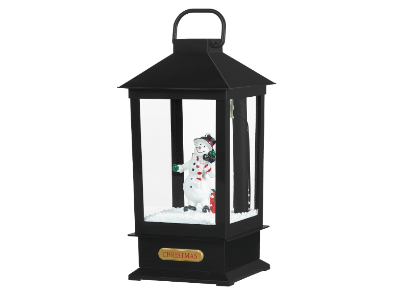 Lanterna de Natal com uma figura de boneco de neve no interior, sobre neve artificial.