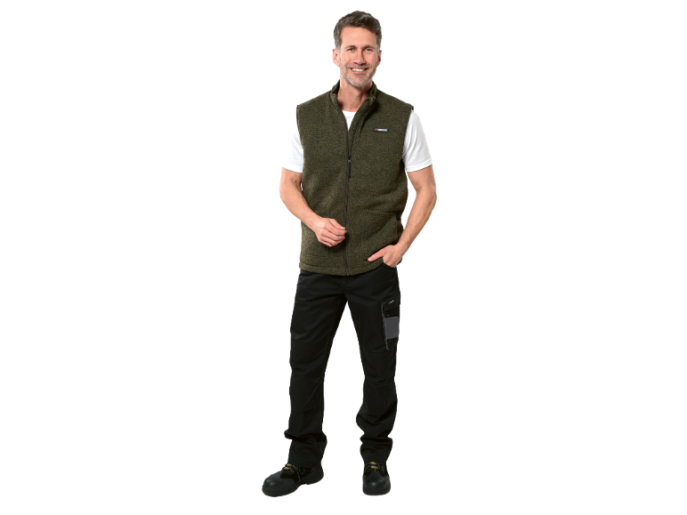 Homem sorridente veste colete verde, t-shirt branca, calças pretas e sapatos de trabalho.