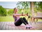 Mulher de t-shirt roxa e leggings pretas a exercitar-se com halteres num tapete de ioga.