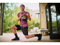 Homem a fazer lunges com um kettlebell preto de 10 kg e roupa desportiva ao ar livre