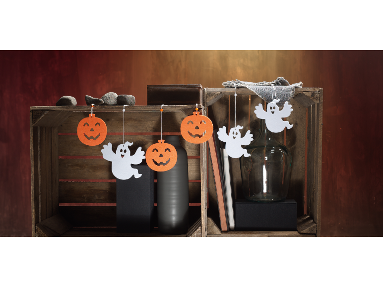 Decorações de Halloween com abóboras e fantasmas, dispostas numa caixa de madeira.