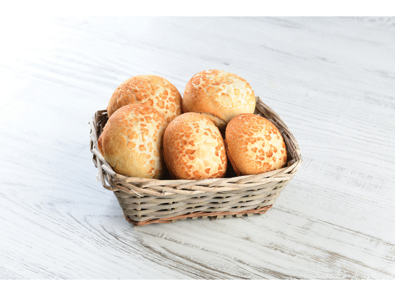 Pãezinhos tigre numa cesta de vime sobre uma mesa de madeira branca.
