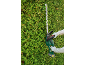Pessoa a aparar uma sebe com um corta-sebes sem fios.