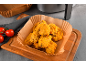 Asas de frango fritas em forro de papel, com tomates e uma fritadeira de ar.