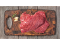 Carne de vaca crua numa tábua de cortar de madeira com alho e alecrim.
