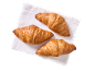 Três croissants dourados sobre um guardanapo branco, vistos de cima.