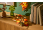 Decoração de outono com velas, abóboras e folhas numa cómoda de madeira.