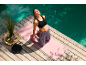 Mulher em tapete de ioga com bloco de ioga junto à piscina, vestindo sutiã desportivo e leggings.