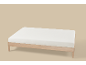 Estrutura de cama de madeira com colchão branco sobre fundo castanho claro