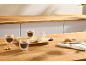Quatro chávenas de café, algumas cheias, outras vazias, com biscoitos numa tábua de madeira e balcão.