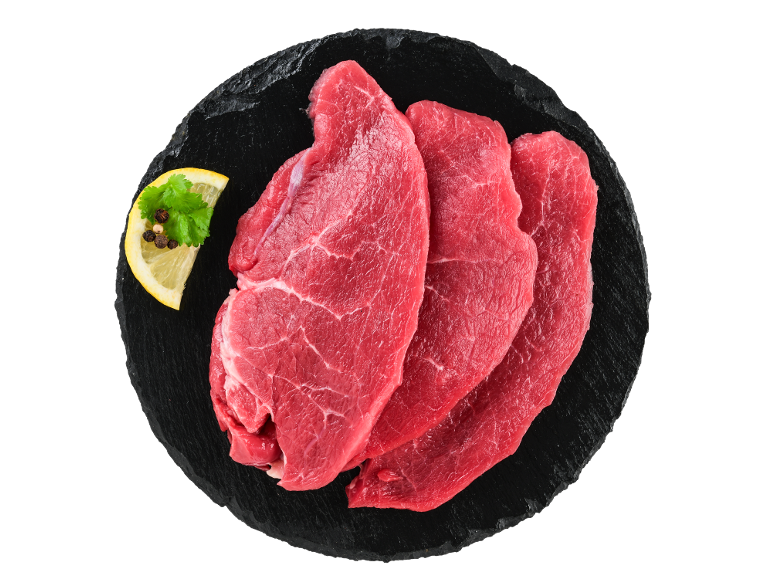 Fatias de carne de vaca Realvalle frescas com limão e especiarias em tábua de ardósia preta.