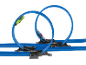 Dois carros de brinquedo a correr numa pista azul com duas grandes voltas contra um fundo preto.