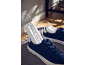 Secador de sapatos inserido em sapatos de lona azul-escuro sobre um tapete cinzento.